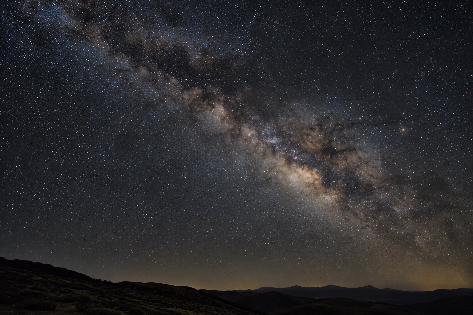 A dense starfield with faint dust lanes and uneven stellar glow.