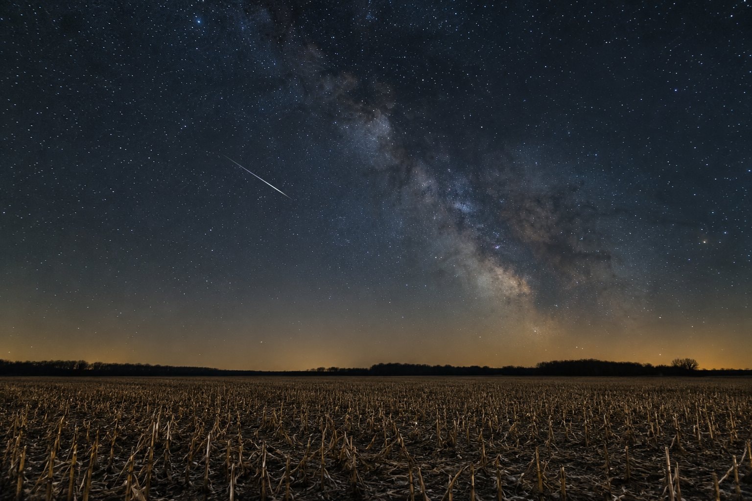 A meteor streak above a harvested cornfield.